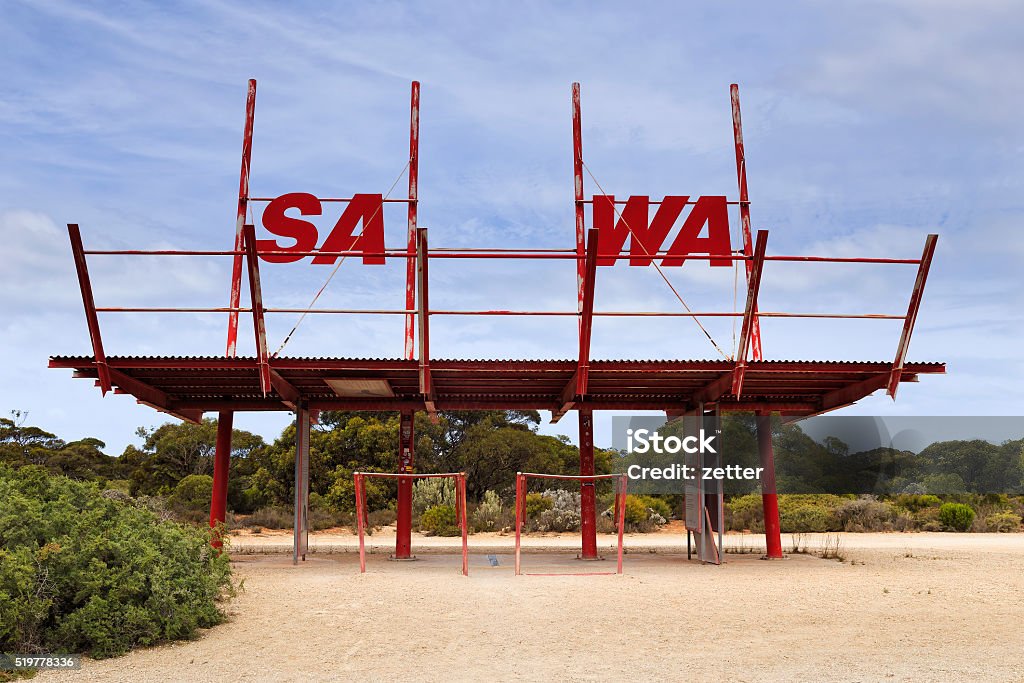 SA WA border sign SA WA border village and border sign in a shape of old metal gate pavilion against blue sky in remote outback. Western Australia Stock Photo