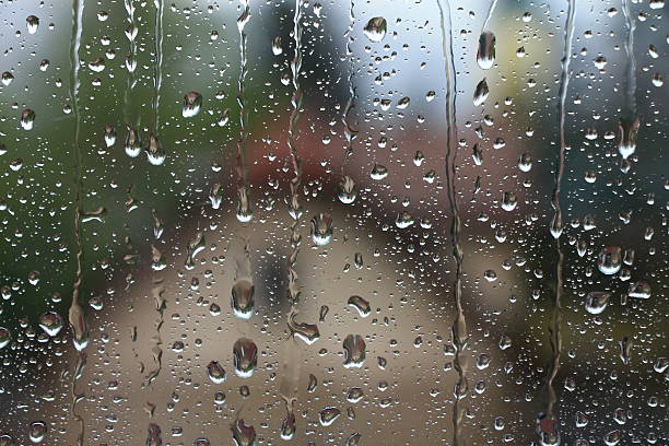 istock Rain drops on window with house and church in background 519783756