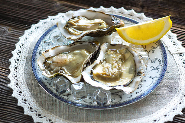 istock Fresh oysters  with ice and lemon on a wooden background 519785800