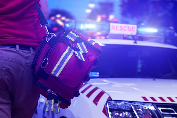 Rescue public service in action Back view of rescue service team member holding a bag and standing next to the vehicle with rotating beacons emergency response stock pictures, royalty-free photos & images