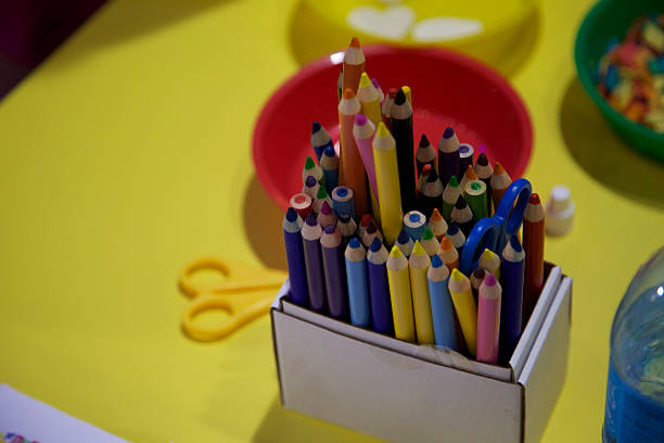 istock Crayons. Colorful wooden pencils scissors in box yellow table 519791318