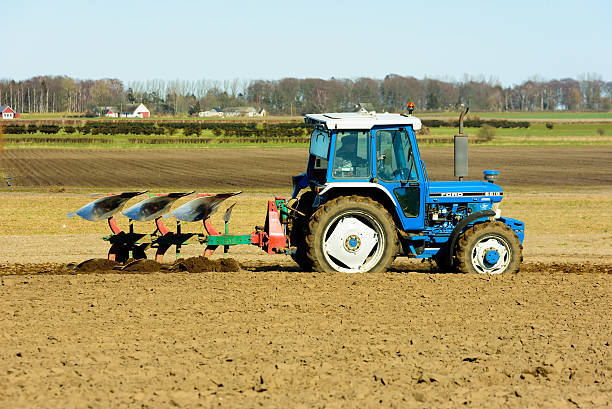 Tractor plowing a field Simrishamn, Sweden - April 1, 2016: Blue and white Ford 6610 tractor plowing down newly spread fertilizer on the field. It is a fine spring day in the country. apply fertilizer stock pictures, royalty-free photos & images