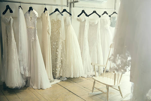 Wedding Dresses Collection of wedding dresses hanging on hangers. A light, airy image of a bridal theme. bridal shop photos stock pictures, royalty-free photos & images