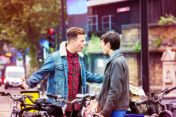 deux amis ayant un argument sur la rue - candid people casual bicycle photos et images de collection