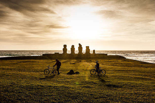 coppia a piedi nel ahu tahai statue moai al tramonto - ahu tahai foto e immagini stock