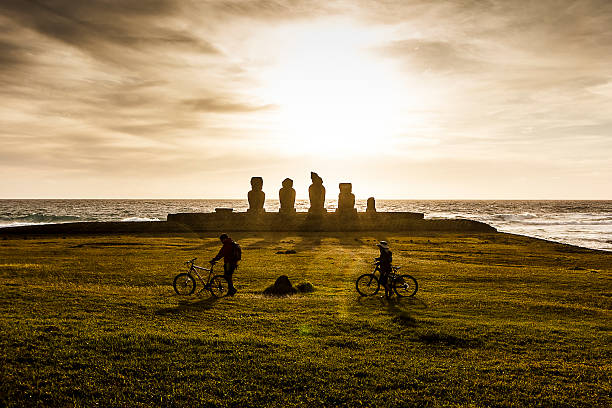 casal caminhar na ahu tahai estátua moai ao pôr do sol - moai statue statue ancient past imagens e fotografias de stock