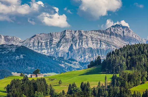 Idyllic landscape in the Alps with green meadows and famous Saentis mountain top in the background, Appenzellerland, Switzerland
