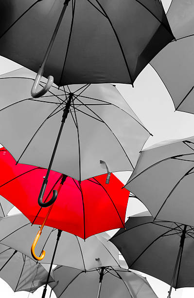 red umbrella standing out from the crowd stock photo