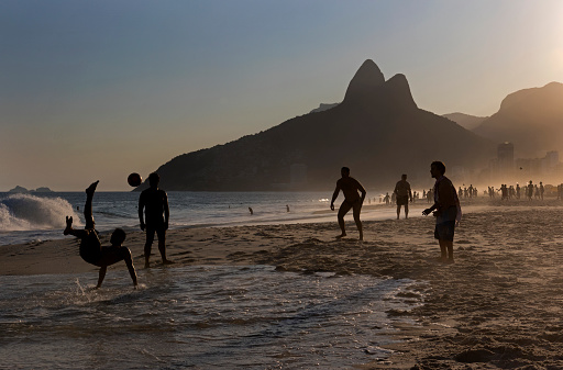 Rio de Janeiro, Brazil – April 8, 2016: Silhouette of local people playing beach football on Ipanema Beach in the afternoon.