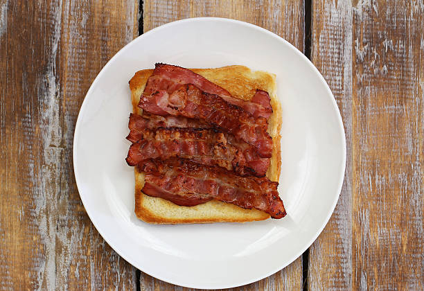 istock Crispy bacon on toast on white plate on rustic wooden 519833506