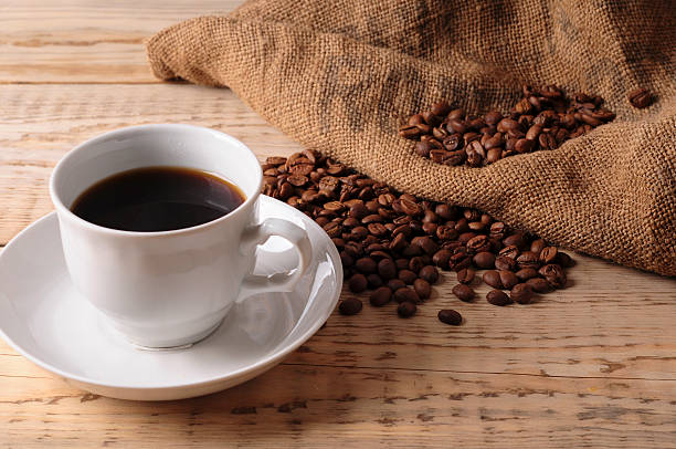 istock Cup with coffee beans on wooden table 519834448