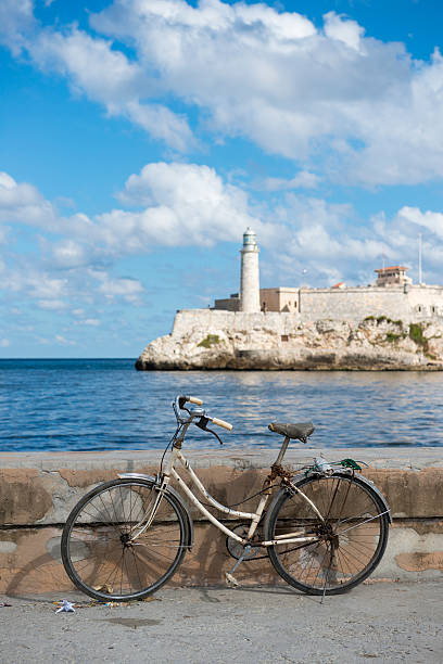 Bicycle in Havana, Cuba Havana, Cuba - December 17, 2014: A bicycle belonging to a fisherman is leaned against a wall at the entrance to Havana Harbor in Havana, Cuba. Across the entrance is the lighthouse at Castillo de los Tres Santos Reyes Magnos del Morro. havana harbor photos stock pictures, royalty-free photos & images