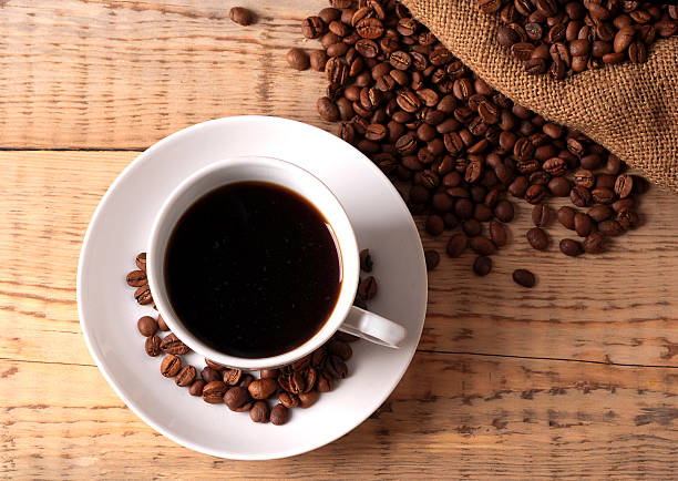 istock Cup with coffee beans on wooden table 519835572