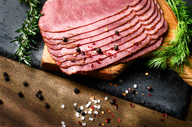 istock fresh sliced beef pastrami surrounded by herbs, wooden chopping board 519836832
