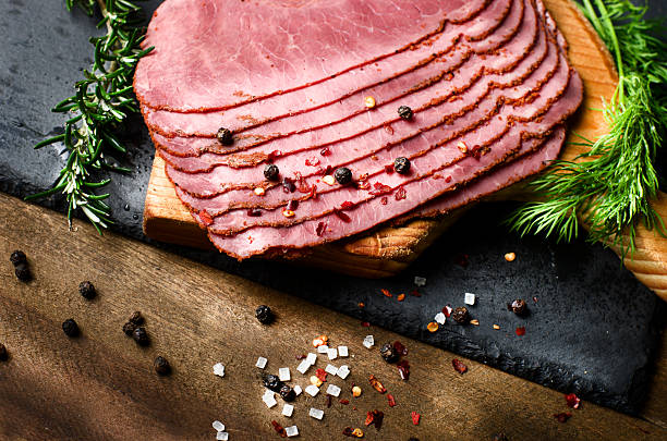 fresh sliced beef pastrami surrounded by herbs, wooden chopping board fresh sliced beef pastrami surrounded by herbs in wooden chopping board pastrami photos stock pictures, royalty-free photos & images