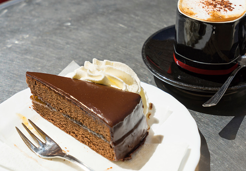 Slice of Sacher Torte or Chocolate cake served with fresh cream and coffee
