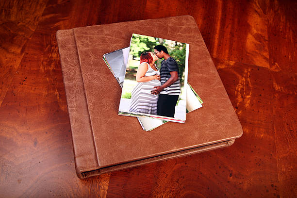 Leather Album Beautiful leather album with photographs of a young African American couple on the cover, sitting on a Mahogany table. old black leather photo album stock pictures, royalty-free photos & images