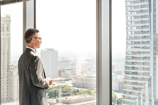 istock Side view of mature businessman looking through office window 519848127