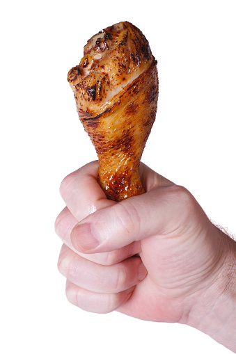 tasty fried chicken drumsticks in male hand isolated on white background