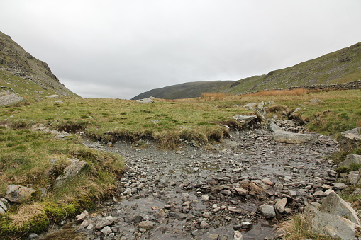 Small stream through hills of the lake district with grass moorland