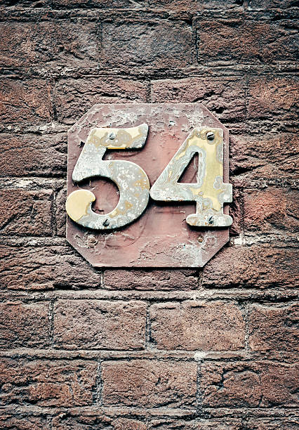 istock Old rusty house number 54, on plate on bricks 519860900