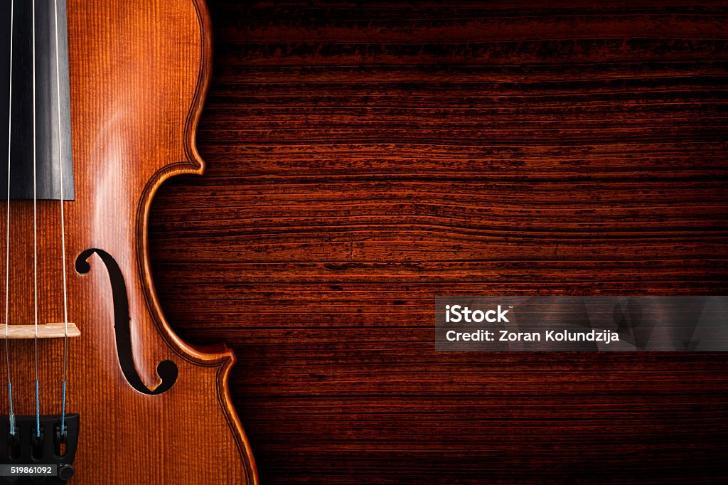 Violin on grunge dark wood background A violin on a grunge wooden board. The violin is lying on a dark red brown weathered wood table. Violin Stock Photo