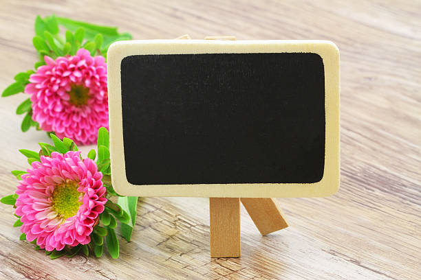 istock Blank mini blackboard with pink daisies on wooden surface 519862102