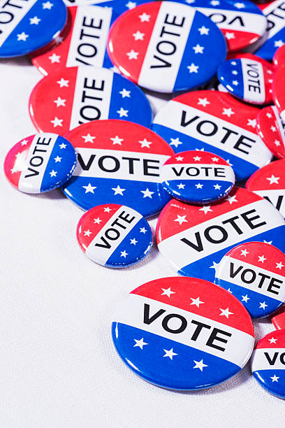 istock Various size Patriotic VOTE buttons on white table cloth 519864184