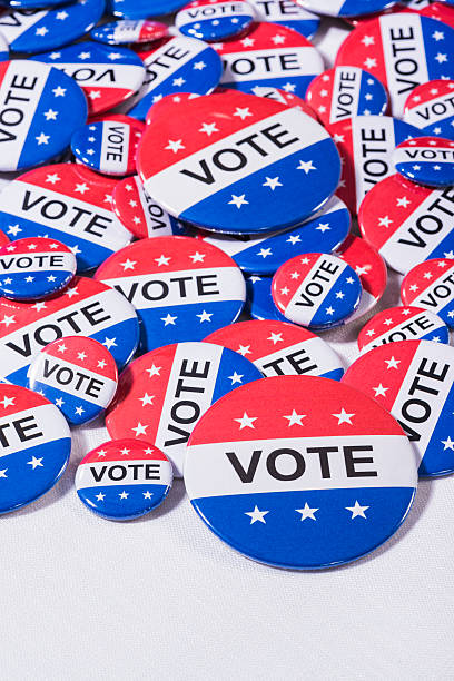 istock Various size Patriotic VOTE buttons on white table cloth 519864240