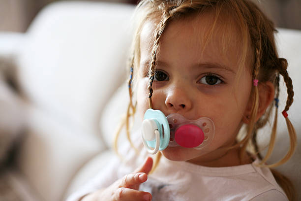 Little girl with two pacifiers. stock photo