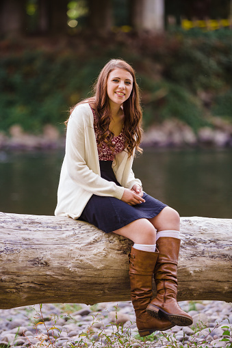 Teen girl poses for a high school senior portrait photo outdoors near a river in Eugene Oregon.