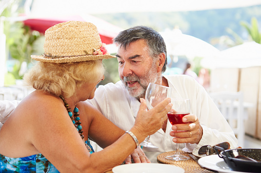 Senior Couple Enjoying Meal In Outdoor Restaurant Smiling To Each Other