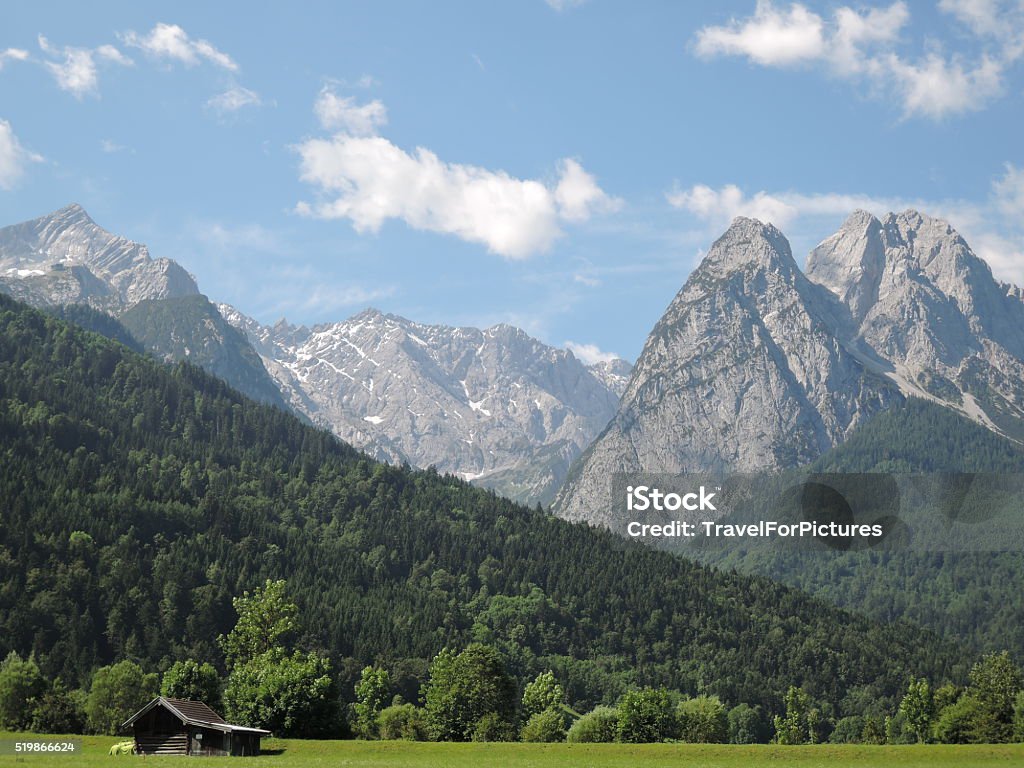 Cabin in Wilderness This is a wood cabin in Garmich, Germany at the bottom of Zugspitze, the tallest point in Germany.  Summer time with snow in the mountains and a perfect warm day at the bottom. Cloud - Sky Stock Photo