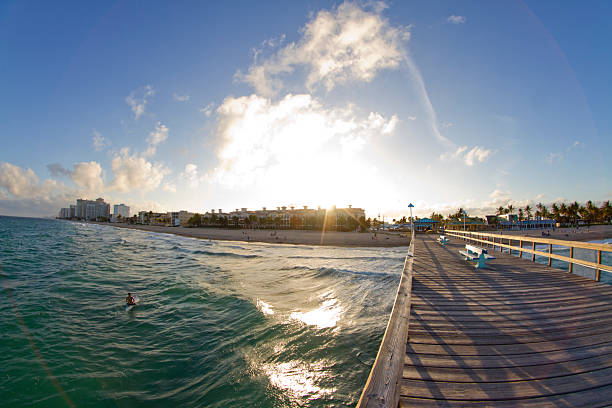 Sun shining on the pier and beach in Miami Tourist enjoying the sun in the water and on the beach next to the pier standing on Miami Beach, Florida. 1 hotel south beach stock pictures, royalty-free photos & images