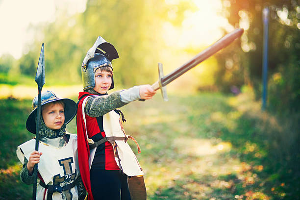 kinder verkleidet als ritter spielen im freien - zuvorkommendes benehmen stock-fotos und bilder