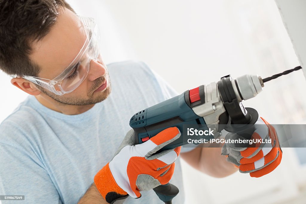 Mid-adult man drilling in wall 30-34 Years Stock Photo