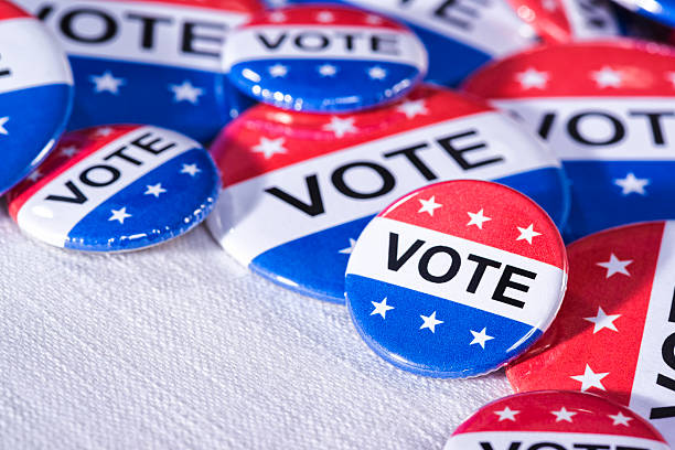 istock Various size Patriotic VOTE buttons on white table cloth 519867996