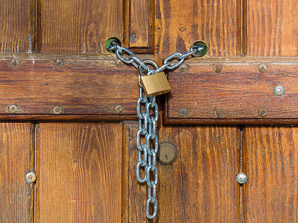 istock Lock  and shiny chain closing a wooden gate 519868044