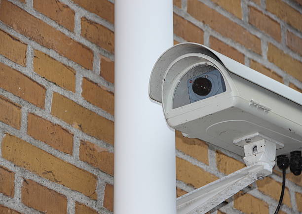 istock Surveillance Camera Closeup mounted on Yellow Brick Wall 519868070