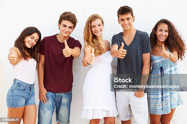 Teenage Group Leaning Against Wall Giving Thumbs Up Stock Photo - Download Image Now