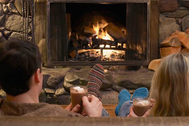 Couple relaxing by a fire Couple relaxing by a fire apres ski stock pictures, royalty-free photos & images