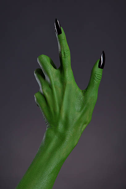 Green witch hand with black nails, Halloween theme, studio shot on black background