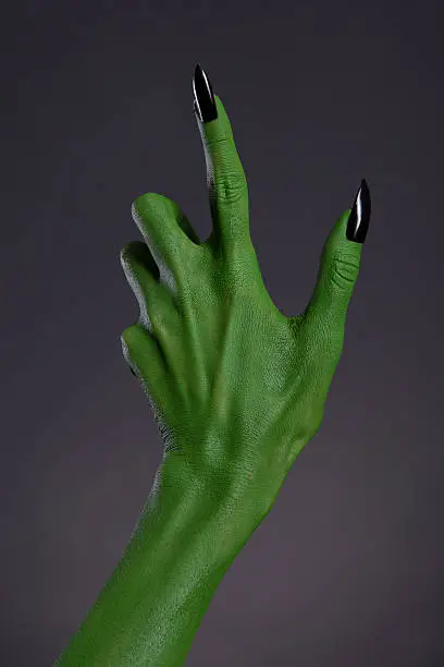 Green witch hand with black nails, Halloween theme, studio shot on black background