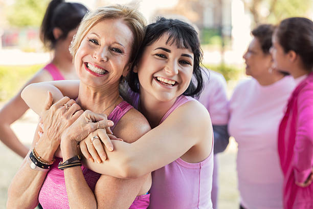 Granddaughter hugs grandmother at charity fun run Beautiful granddaughter hugs her granddmother at breast cancer charity fun run. The women are wearing pink tank tops. food chain stock pictures, royalty-free photos & images