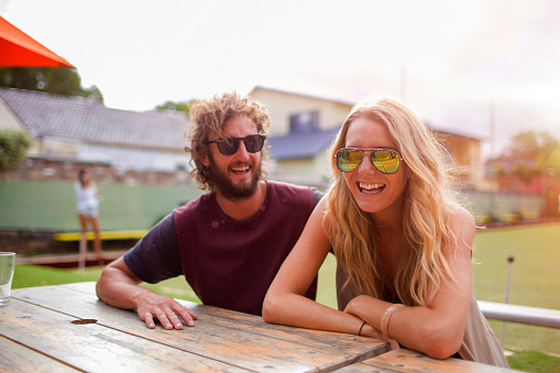 A couple or friends at an Australian lawn bowls club having a drink at sunset and laughing