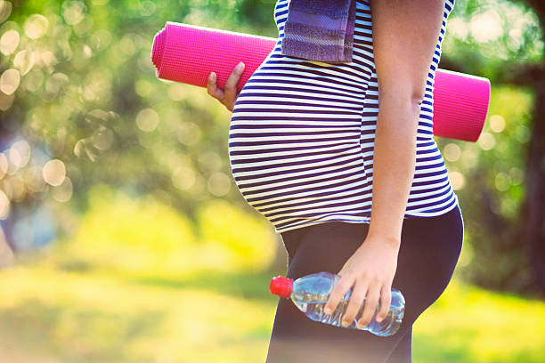 Staying fit while pregnant Young pregnant woman preparing for an exercise outdoors on a sunny day pregnant exercise stock pictures, royalty-free photos & images