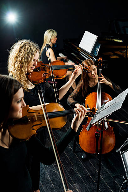 Female quartet. Group of women playing musical instruments. string ensemble stock pictures, royalty-free photos & images