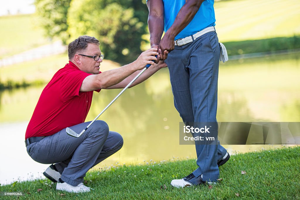 Golf Pro Teaching Male Golfer Golf pro teaching beginner golfer on driving range. Assistance Stock Photo