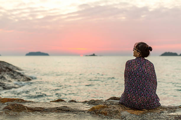 istock Lonely woman sitting on seashore after sundown. 519890638
