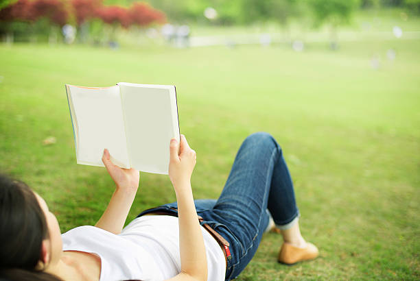 istock beautiful girl with book on the grass 519893988